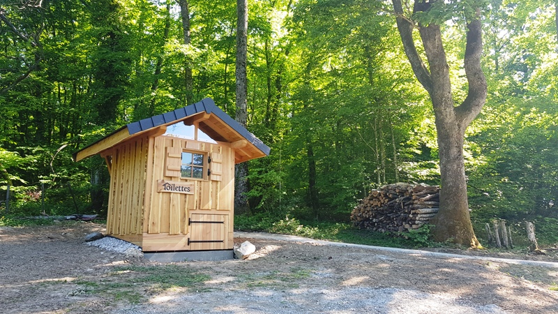 Une toilette sèche installée à coté d'un tas de bois