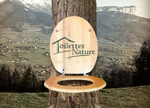 Photo de la nouvelle brochure de Toilettes Nature avec un abatant de WC sur le tronc d'un arbre