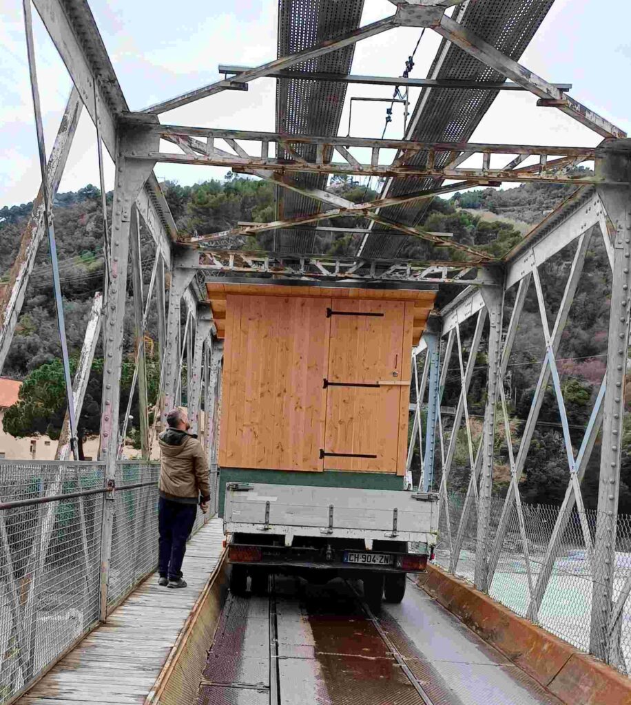 On voit le passage du camion et de la toilette sous le pont métallique